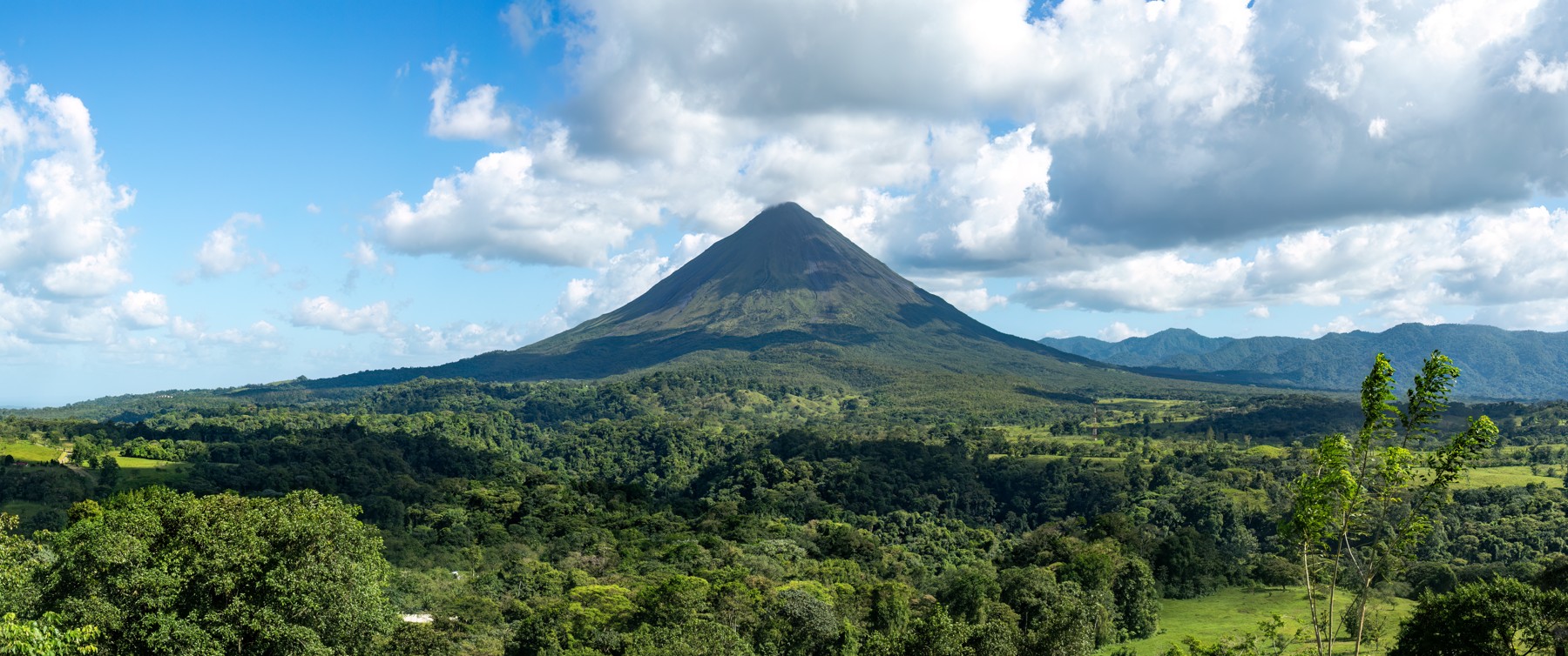 Panoramic view of Arenal Volcano’s full cone above green forest